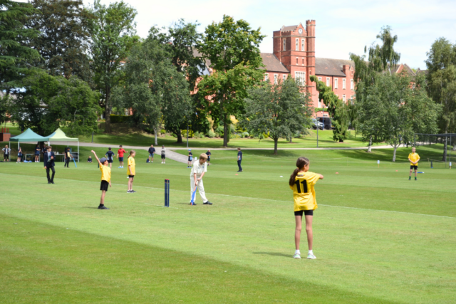 Children play a cricket match in front of the Trent College main school building.