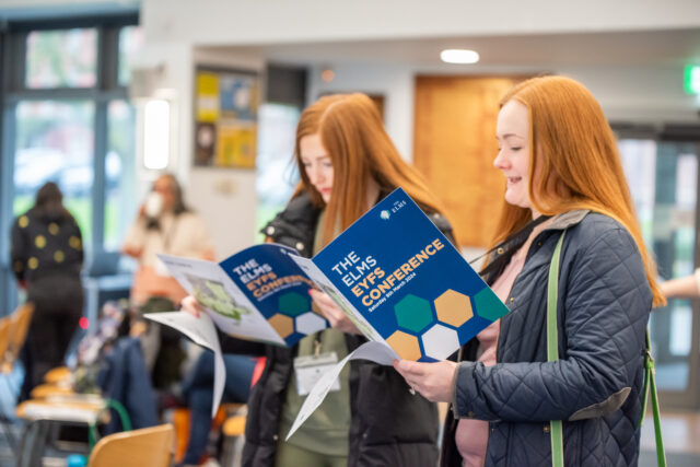 Two delegates to The Elms EYFS Conference read the event event programme.