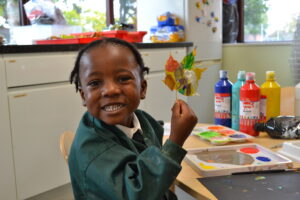 A Reception child enjoying a painting activity in the classroom